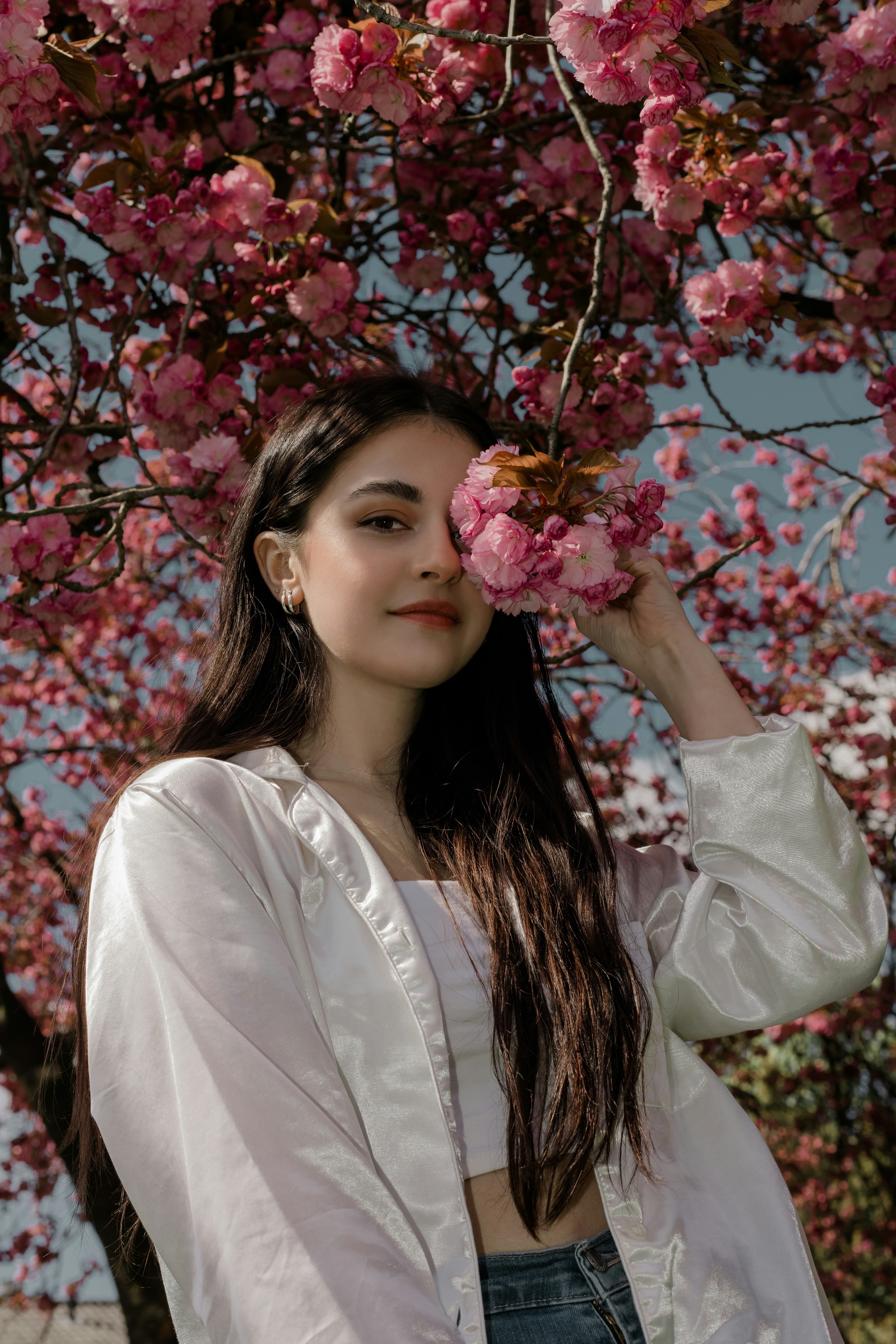 woman in white long sleeve shirt holding pink flowers